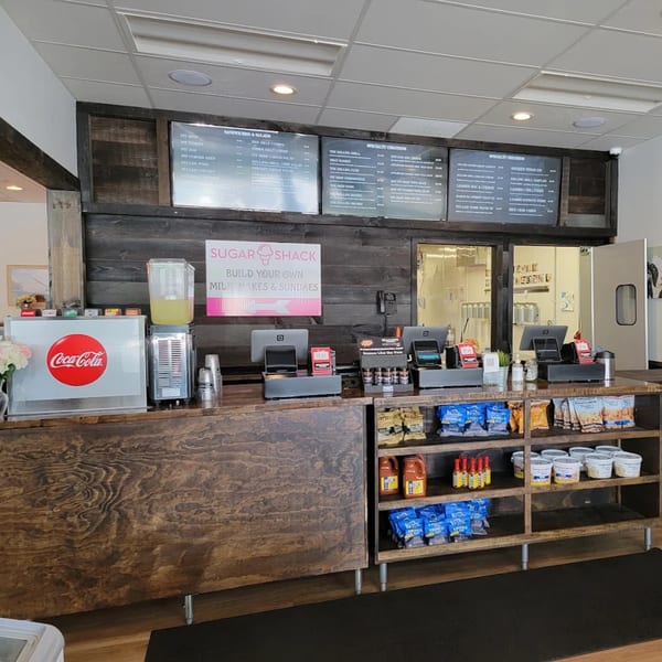 The Rolling Grill Pit Beef counter with menu boards, Coca-Cola dispenser, and snack shelves.